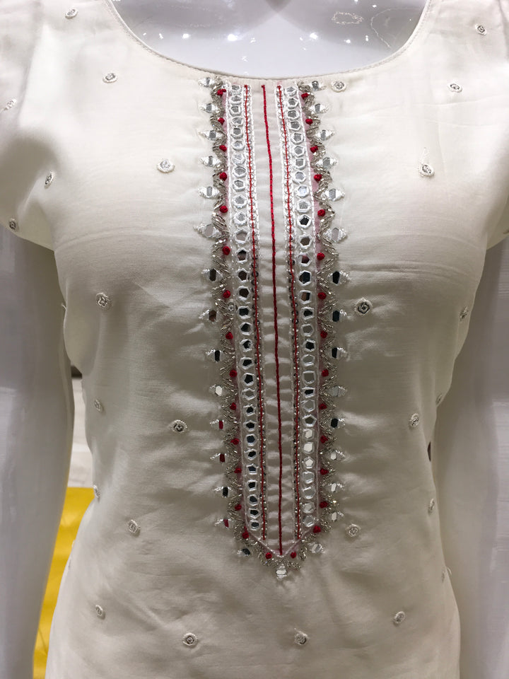 Cream Chanderi Cotton Straight Cut Salwar Kameez with thread embroidery, mirror detailing, pencil pant, and bandhani printed chiffon dupatta.